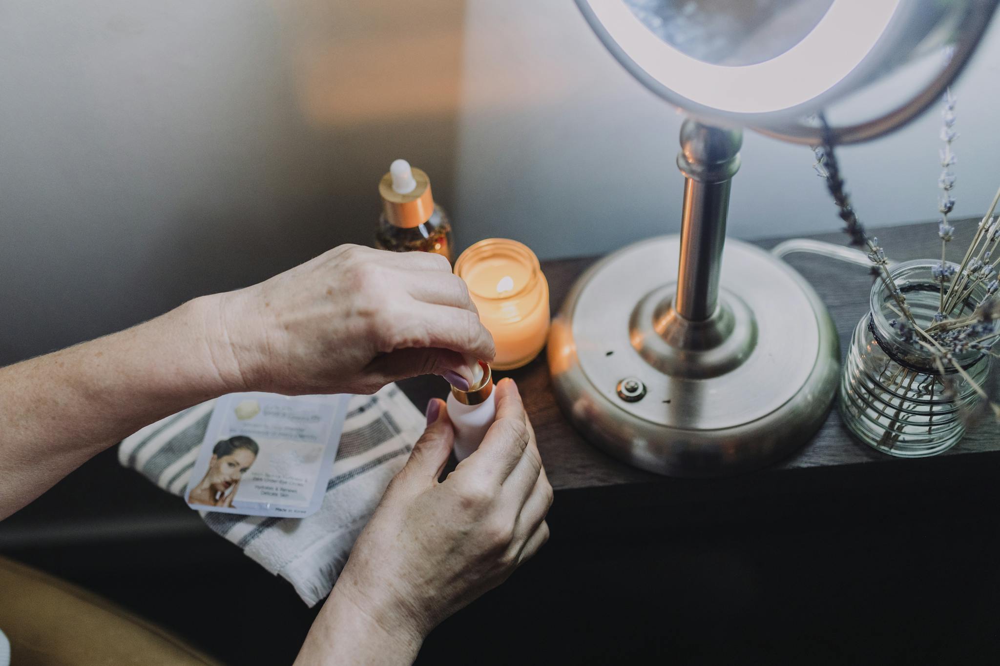 A serene skincare ritual by candlelight featuring hands applying essential oils, promoting relaxation and self-care.